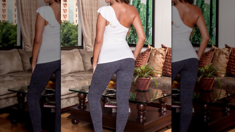 Mujer vistiendo un top blanco ajustado y leggings grises