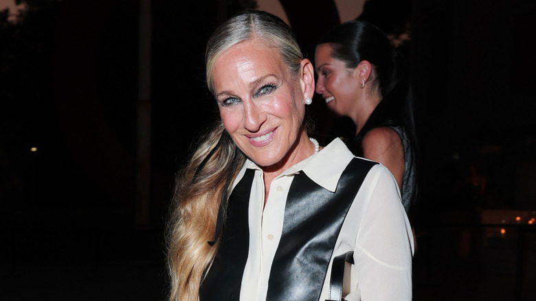 Sarah Jessica Parker posando en un evento luciendo un top blanco y negro y el pelo recogido en una coleta baja.