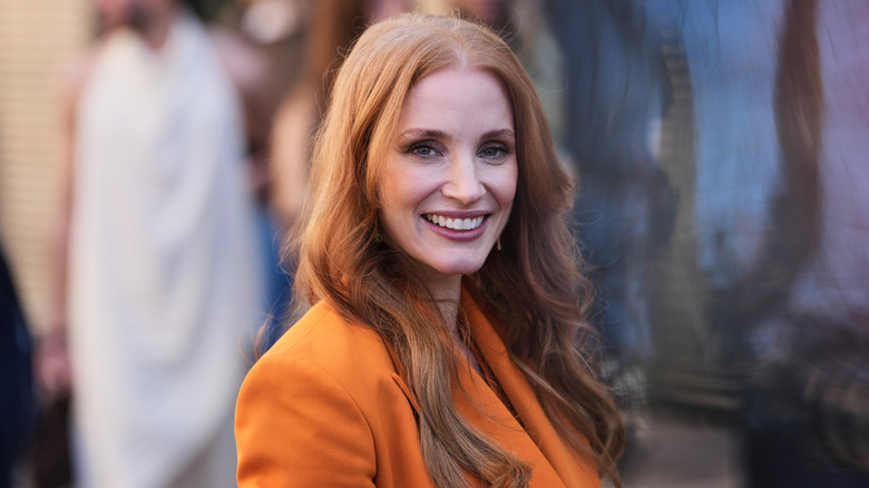 Jessica Chastain posando en un evento luciendo un vestido blazer naranja.