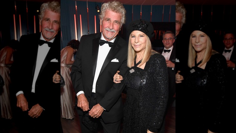 Barbra Streisand con un traje negro brillante y un sombrero del brazo de su esposo James Brolin en esmoquin.