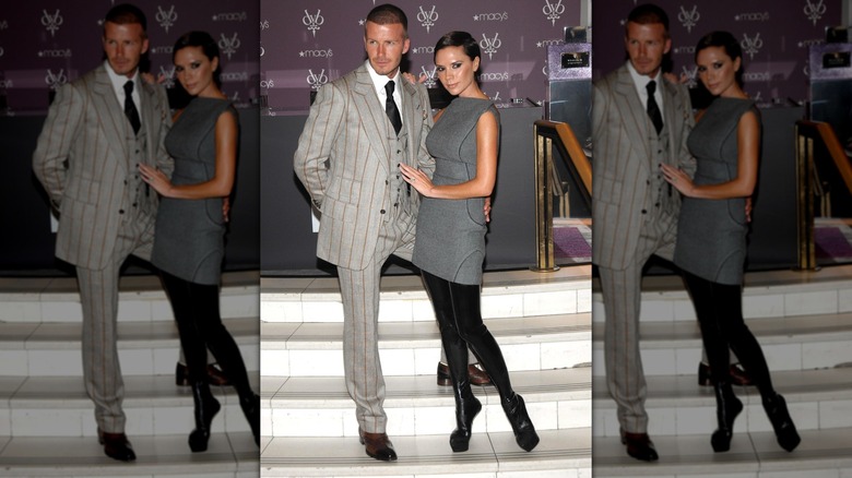 Victoria Beckham con vestido gris y botas con David Beckham