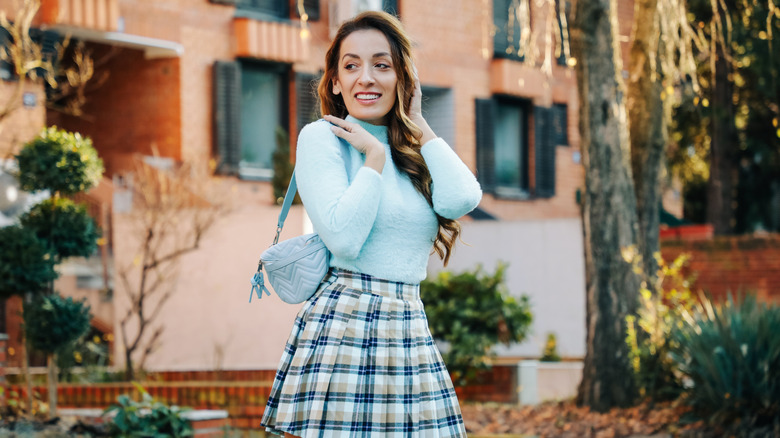Mujer vistiendo suéter azul y falda a cuadros
