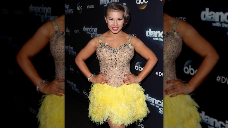 Bindi Irwin con un corpiño de pedrería y una falda de piel amarilla adjunta.