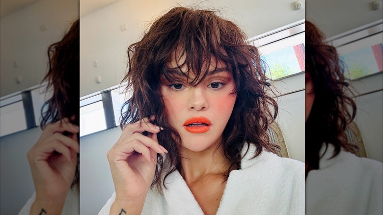 Selena Gomez posa en bata con cabello rizado y labios naranjas