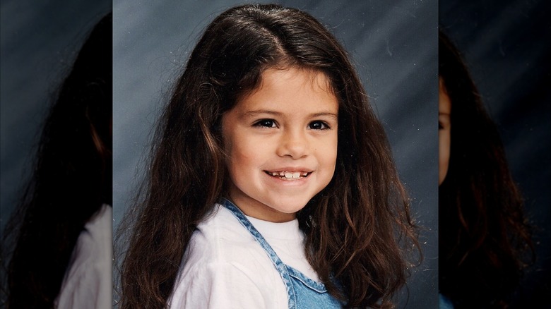 Una joven Selena Gomez con una camisa blanca y un vestido de mezclilla.