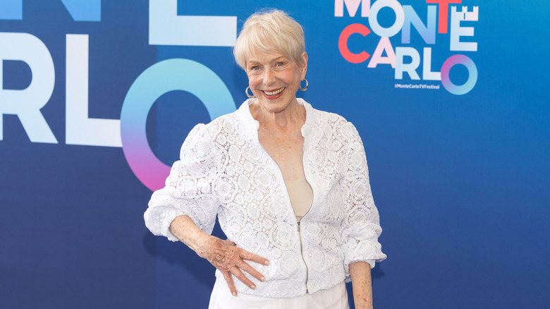 Karen Grassle posa con la mano en la cadera, luciendo un conjunto completamente blanco y aretes de aro.