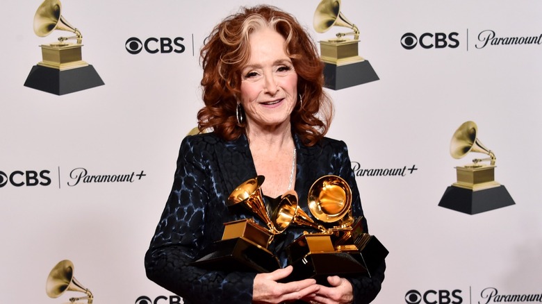 Bonnie Raitt viste una chaqueta negra y azul con grandes aretes de aro y su característico mechón gris contra sus rizos rojos brillantes en la 65.a entrega de los premios GRAMMY en Crypto.com Arena en Los Ángeles, California, en febrero de 2023.