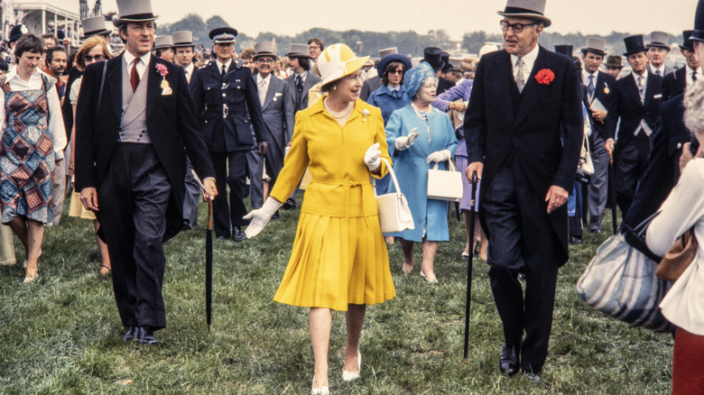 La reina Isabel caminando con un traje de falda amarilla.