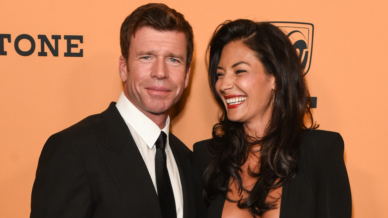 Taylor Sheridan asiste a un evento de alfombra roja de Yellowstone mientras su esposa Nicole Sheridan se ríe mientras posa junto a él.