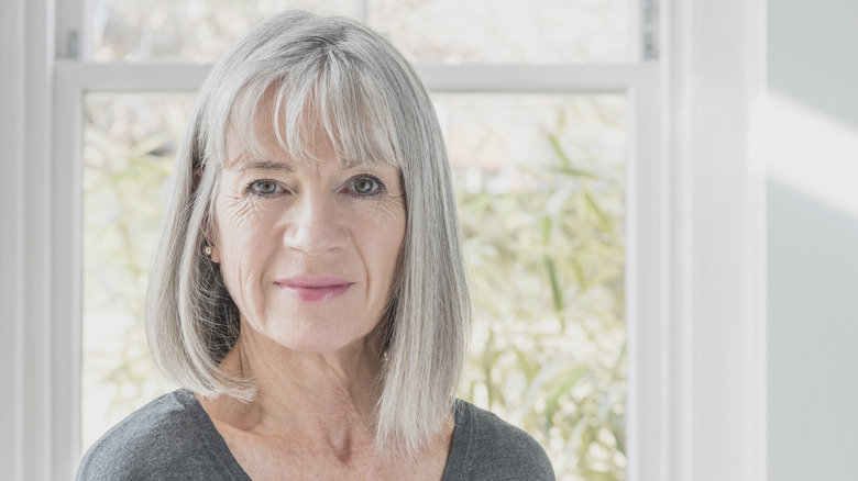 Una mujer sonríe con un largo bob gris.
