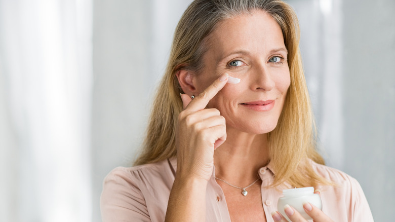 Una mujer mayor aplicando crema hidratante