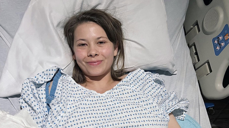 Bindi Irwin en una cama de hospital y una bata después de su cirugía de endometriosis