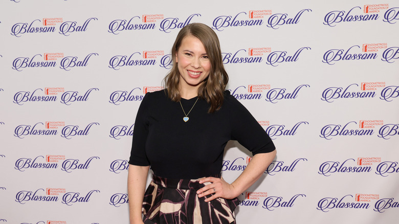 Bindi Irwin con camisa negra y falda estampada en el EndoFound Blossom Ball 2024