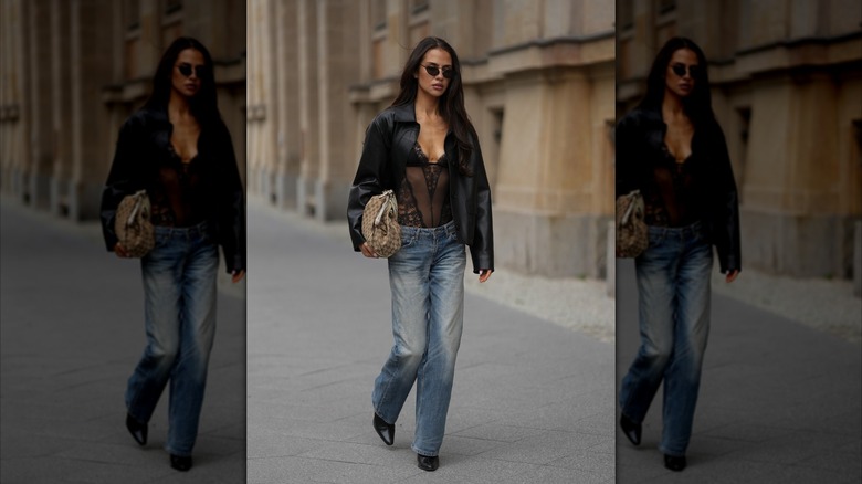 Una mujer viste jeans azules de pierna recta, un body de encaje negro y una chaqueta negra durante la Semana de la Moda de Berlín 2026.