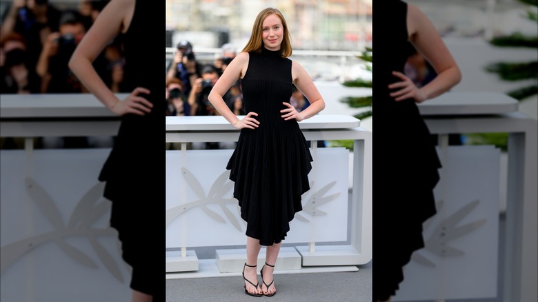 Hannah Einbiner con un vestido negro con volantes y sandalias con punta abierta.