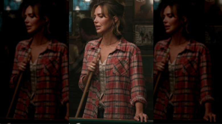 Belle Skinner con una camisa a cuadros roja con un top beige y jeans.