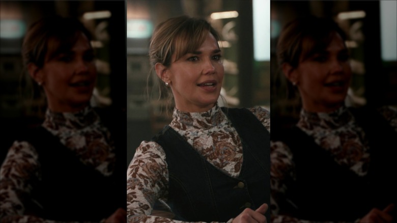 Belle Skinner con un jersey de cuello alto floral y un chaleco