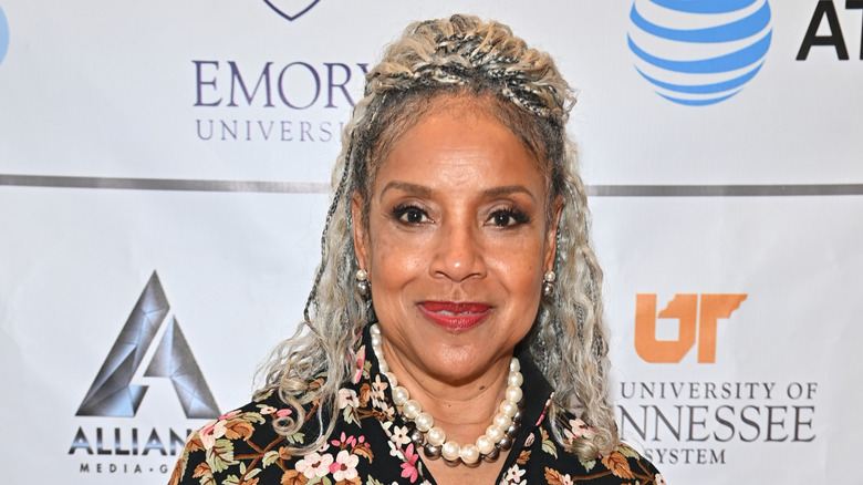 Phylicia Rashad sonríe con trenzas plateadas luciendo un vestido de flores
