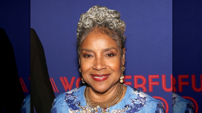 Phylicia Rashad sonríe luciendo un moño y aretes de perlas