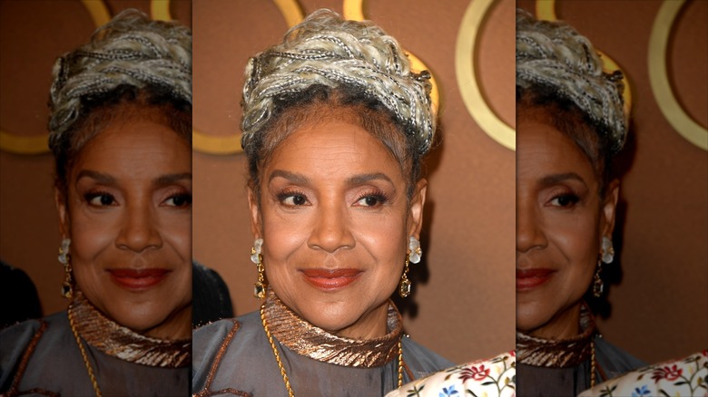 Phylicia Rashad sonríe luciendo joyas de oro y el pelo recogido en un moño trenzado.