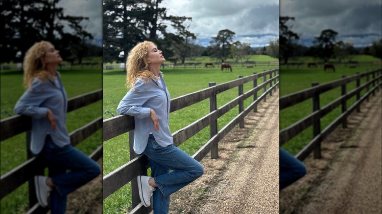 Nicole Kidman posa afuera, apoyada contra una valla.