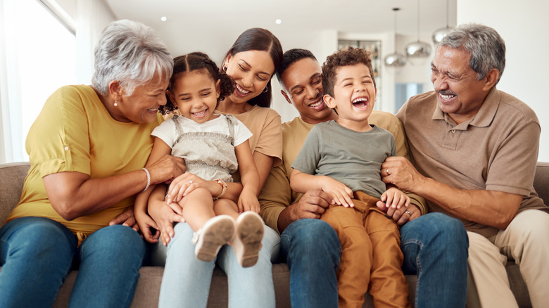 Familia riendo juntos sentados en el sofá