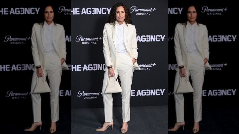 Minnie Driver posando en un evento con un traje completamente blanco.