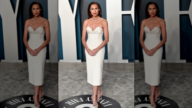 Minnie Driver posando en un evento luciendo un sencillo vestido blanco sin tirantes.