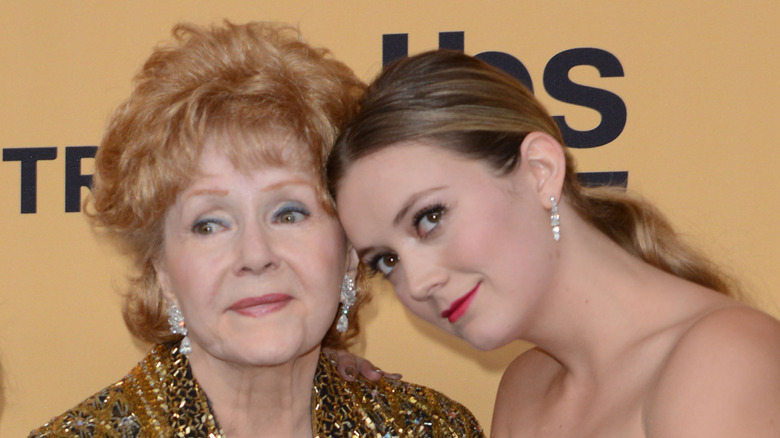 Debbie Reynolds y Billie Lourd posan juntas con maquillaje glamoroso en un evento.