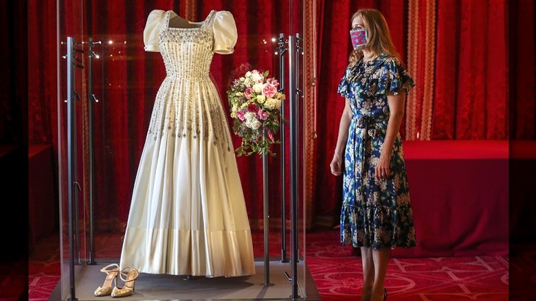 La princesa Beatriz, con una máscara, admira su vestido de novia expuesto