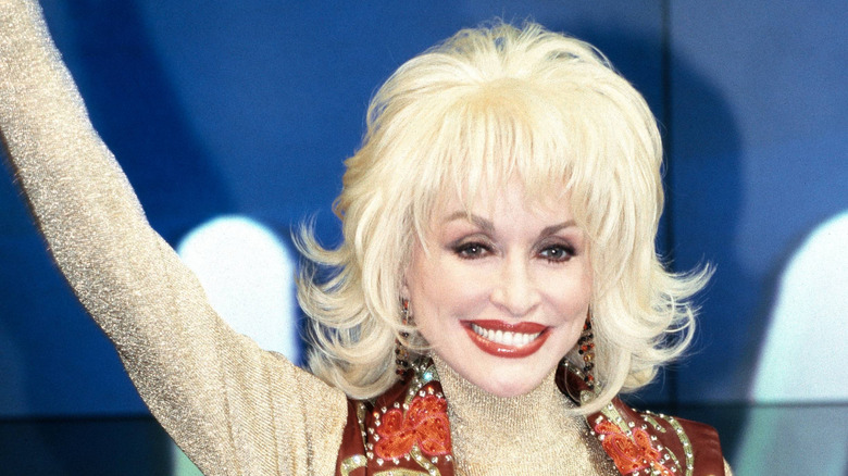 Dolly Parton con chaleco marrón y peinado bob
