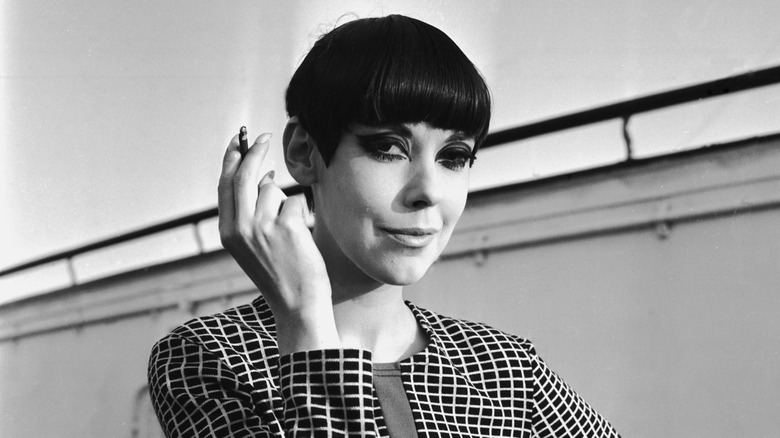 Peggy Moffitt sonríe sosteniendo un cigarrillo en 1965