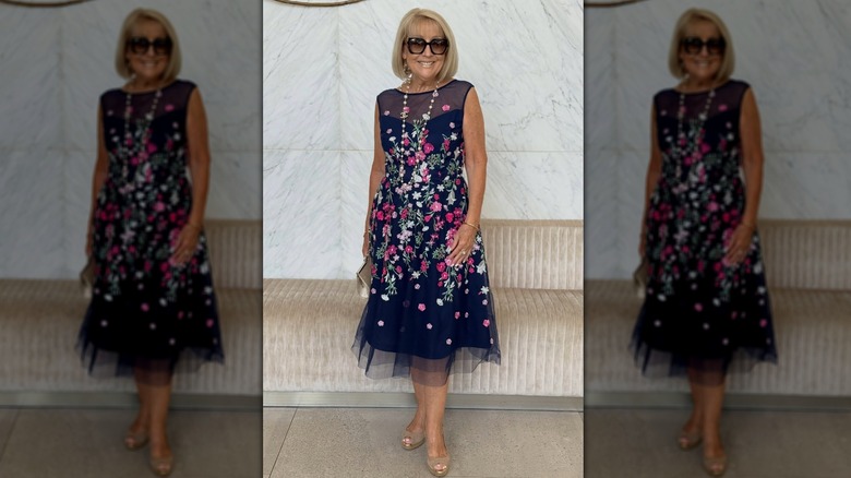 Mujer mayor con un vestido floral con una capa transparente.