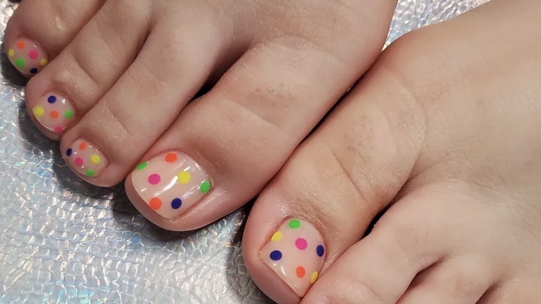 Pedicura de lunares con lunares rosas, verdes, azul marino, naranja y amarillo.
