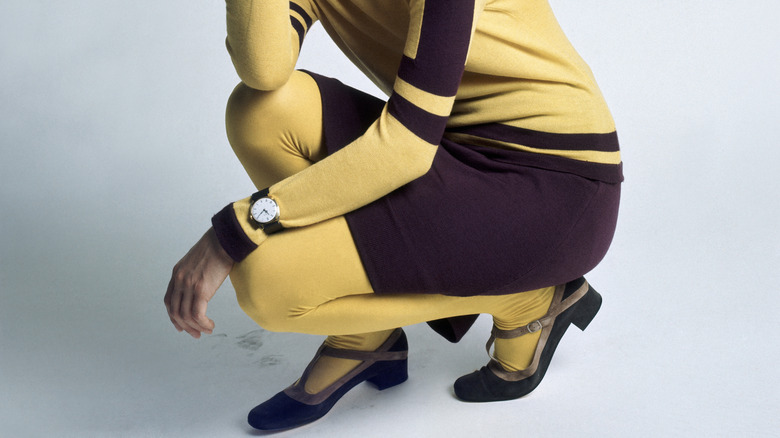Primer plano de las piernas de una mujer que usa medias amarillas y un vestido amarillo y morado.