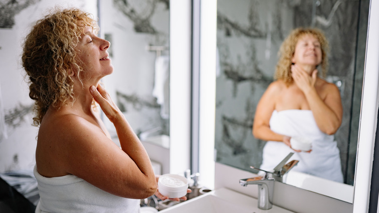 Una mujer aplicándose crema en el cuello.