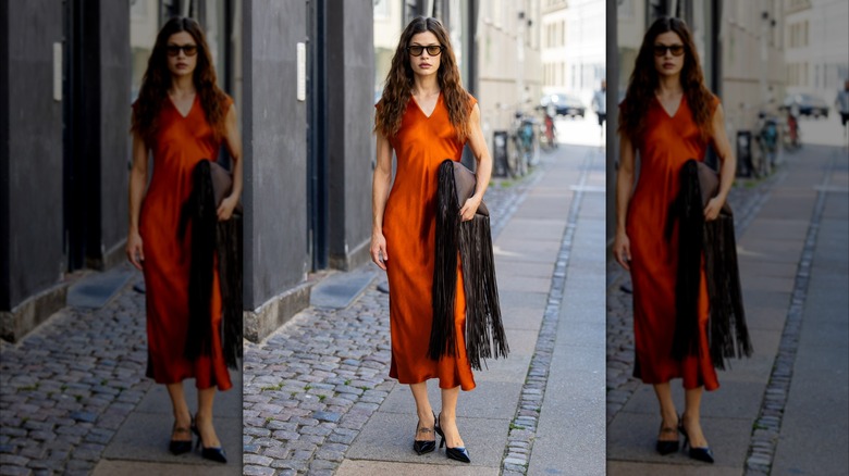 Una mujer que llevaba un vestido de satén naranja quemado.