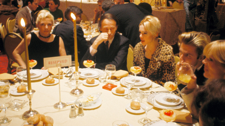 Edie Sedgwick sentada en una mesa en un evento con un abrigo con estampado de leopardo.