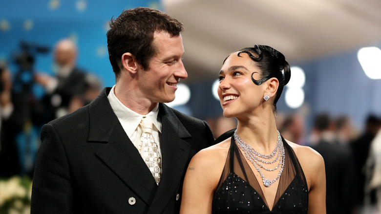 Callum Turner y Dua Lipa se sonríen en una alfombra roja