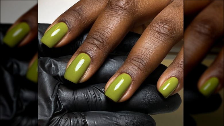 Una manicura corta con esmalte de uñas verde oliva.