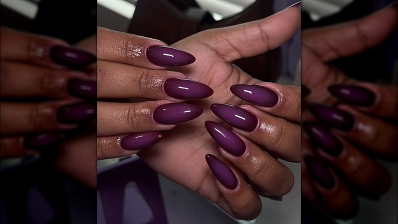 Una manicura almendrada con esmalte de uñas morado.