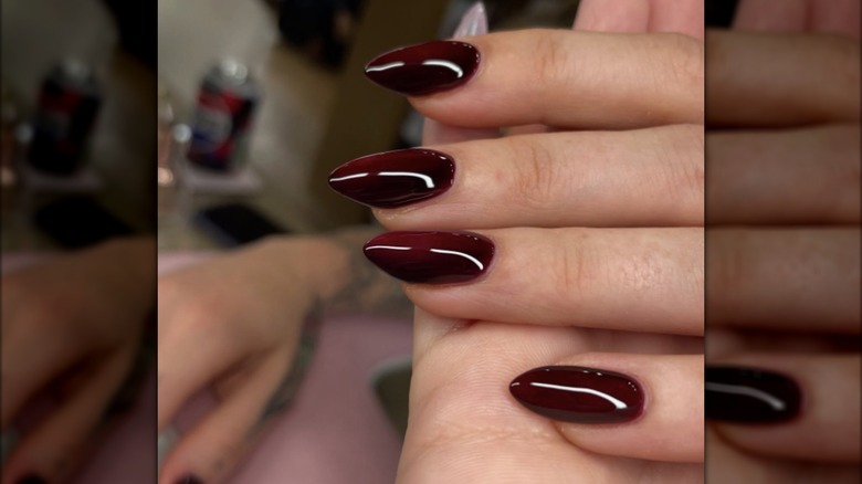 Una manicura en garras con esmalte de uñas color burdeos oscuro.