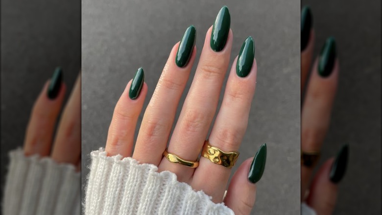 Una manicura larga y redonda con esmalte de uñas verde bosque oscuro.