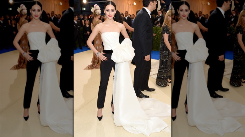 Emmy Rossum asiste a la Met Gala 2017 con pantalones sastre negros y un top blanco sin tirantes con cola
