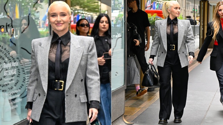 Hayden Panettiere vistiendo pantalones negros holgados con un top negro y una camisa negra transparente, con un cinturón llamativo y una chaqueta gris en septiembre de 2024.
