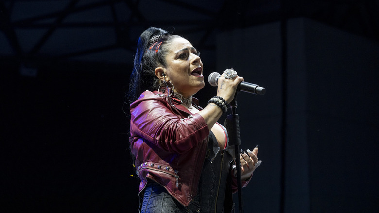 Lisa Vélez actuando en el escenario con una chaqueta de cuero roja y una coleta alta.