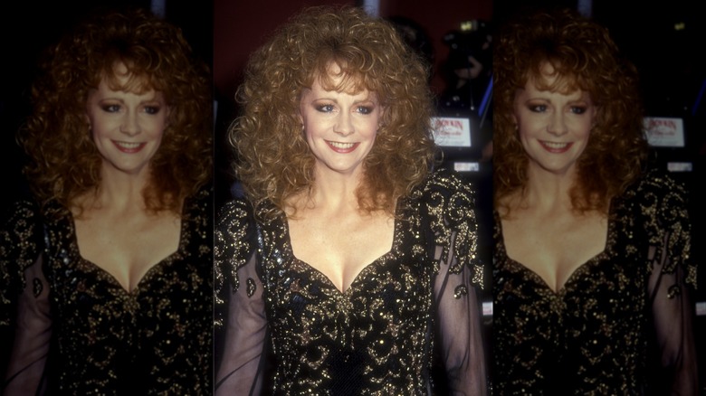 Reba McEntire con un vestido negro y dorado con mangas transparentes y cabello voluminoso en los Premios de la Academia de 1991.
