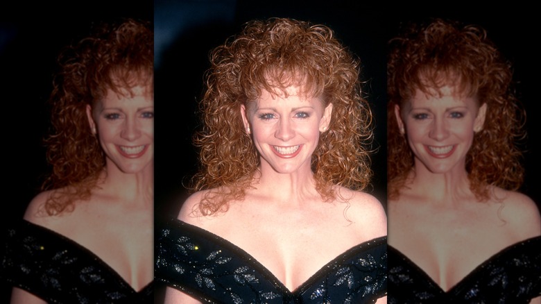 Reba McEntire con un vestido negro con hombros descubiertos y cabello rizado definido en los People's Choice Awards de 1992.