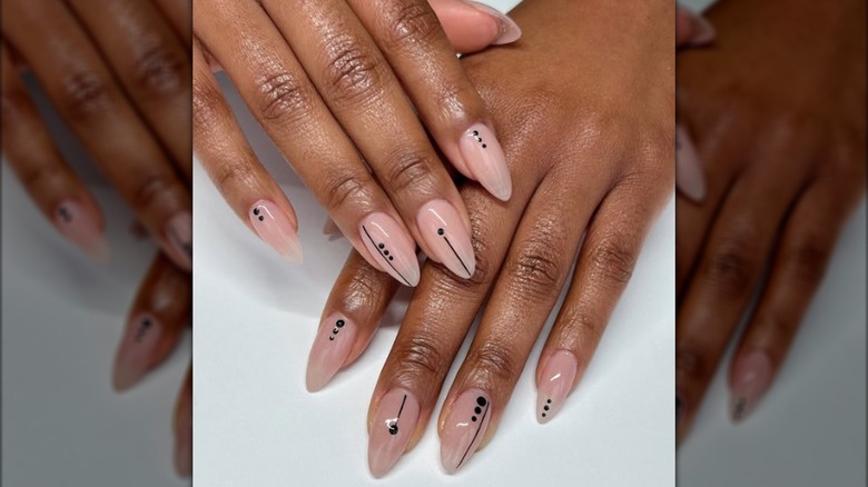 Manicura minimalista en forma de almendra con diseños geométricos en negro.