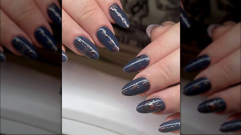 Manicura redonda con esmalte de uñas azul grisáceo y diseños celestes.